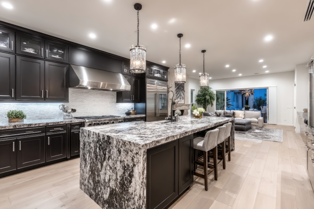 Open-plan modern kitchen with dark cabinetry, granite island, and hardwood floors
